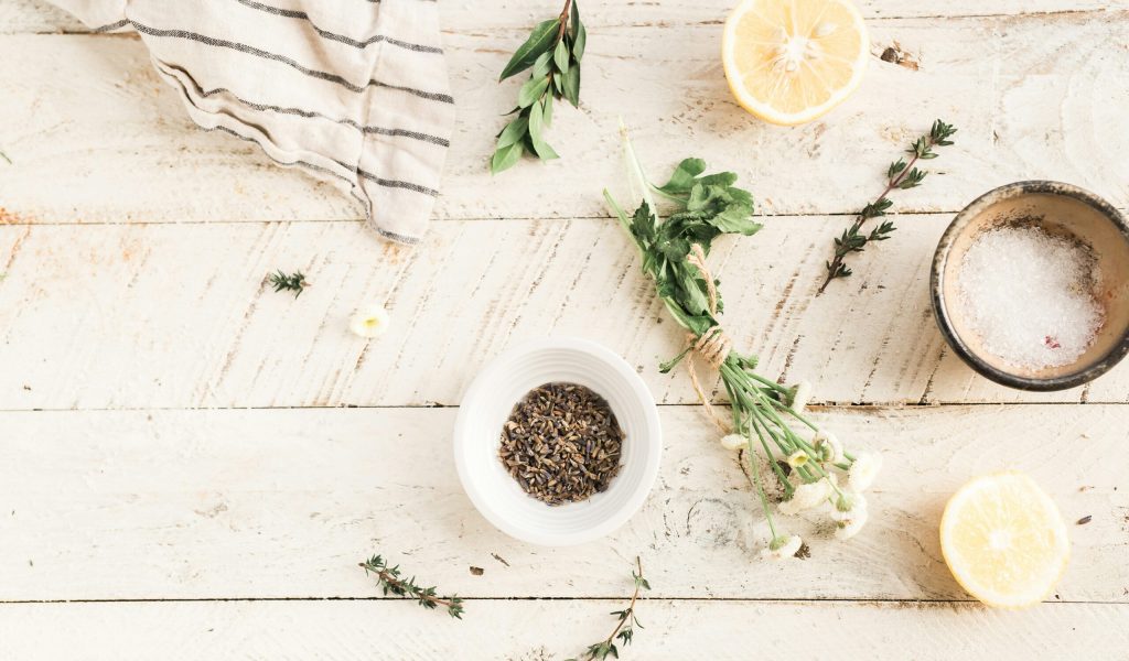 wooden background, with bowl of herbs lemon and other green leafy herbs